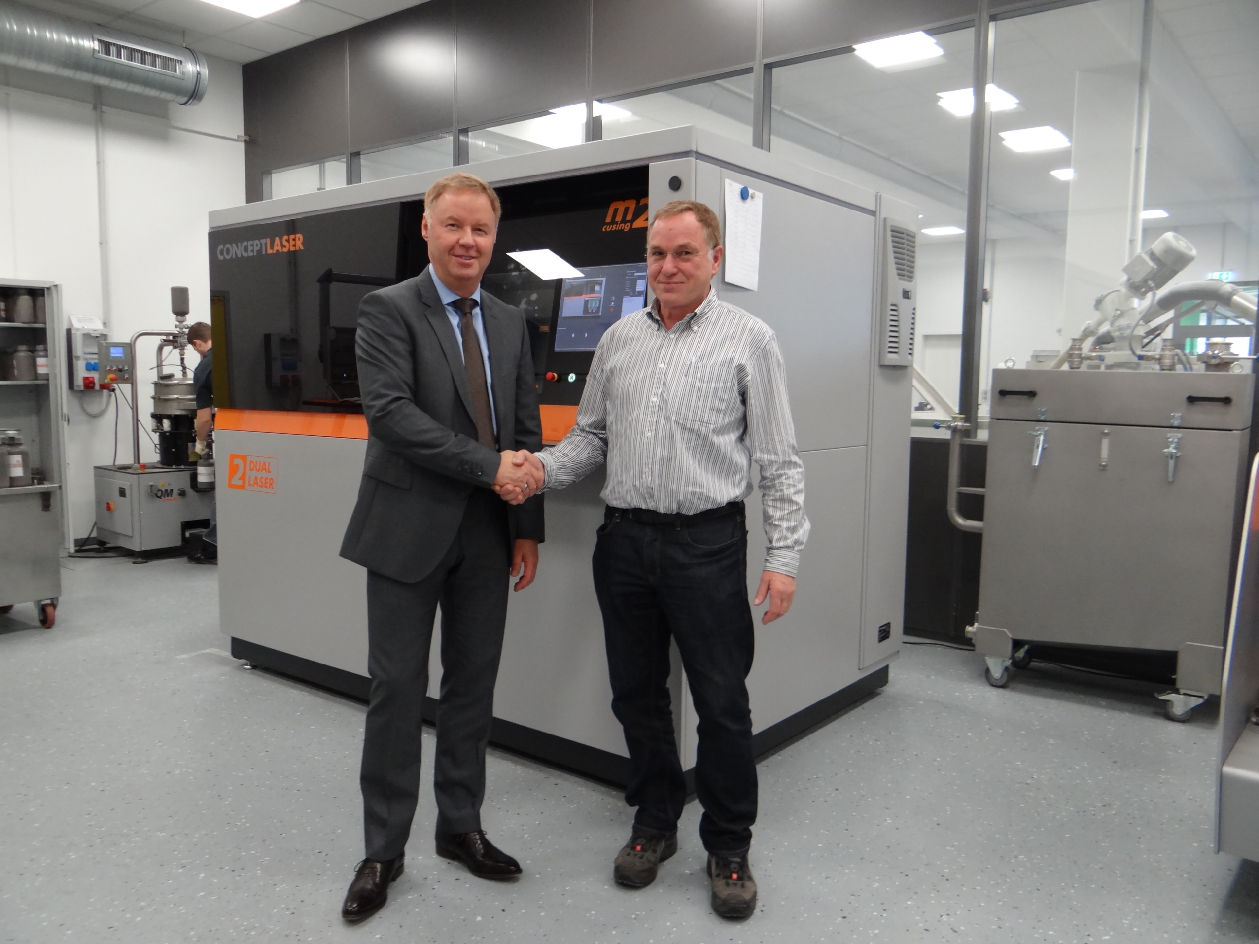 Harald Henkel, MD of FKM Sintertechnik GmbH, and Oliver Edelmann, vice president sales and marketing at Concept Laser GmbH, in front of a laser sintering machine.