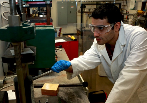 MIT graduate student Zack Cordero demonstrates a uniaxial press used for consolidating loose powder into a pellet.