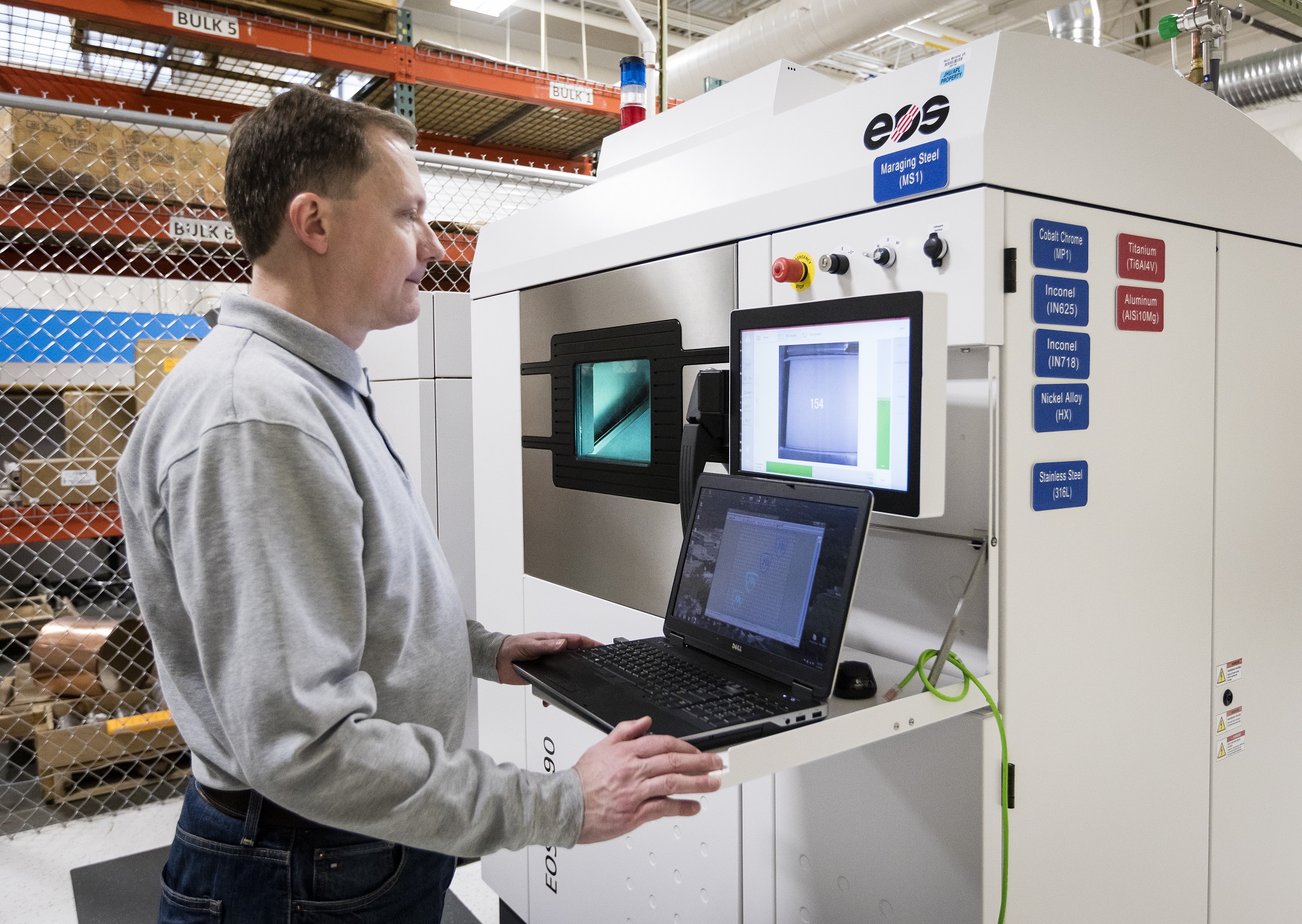 AM engineer John Slotwinski checks the progress of complex metal parts being made inside APL’s metal powder bed fusion additive manufacturing system. Photo courtesy JHU/APL.