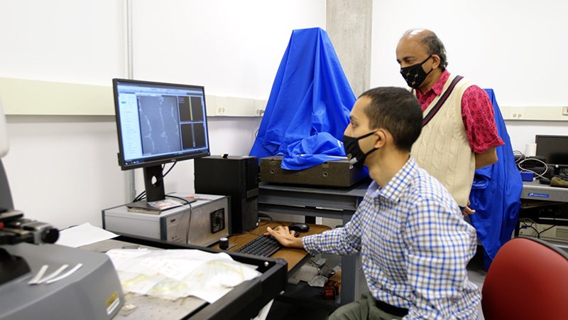 Anirudh Udupa (seated) and Srinivasan Chandrasekar (standing) analyze metal surfaces to look for deformations created during cutting to determine how applied organic films affect the quality of the cut. Photo: Purdue University/Erin Easterling.