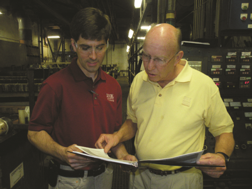 Chris Henderson (left) information manager, and Jim Jones, vice president, review reports from one of Dixie Industrial Finishing's rack lines.