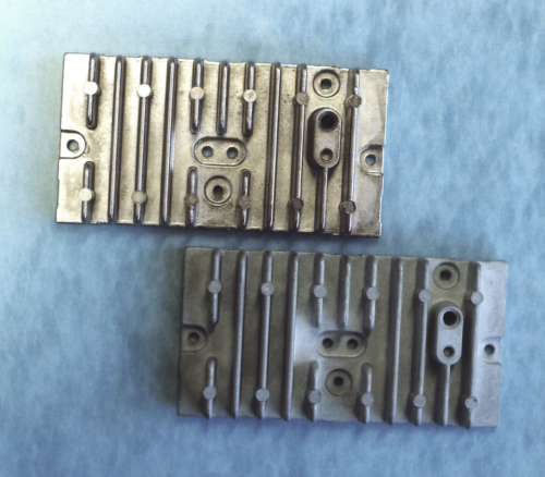 Figure 2: Cast aluminum alloy “383” before (bottom) and after (top) plating with electroless nickel.